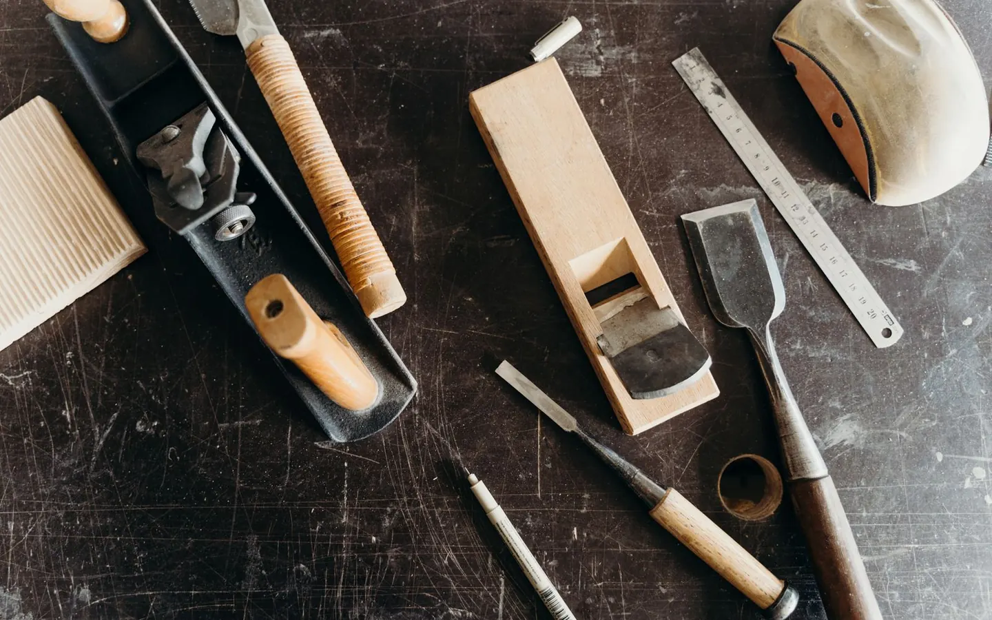 An assortment of woodworking hand tools laid out on a workshop table