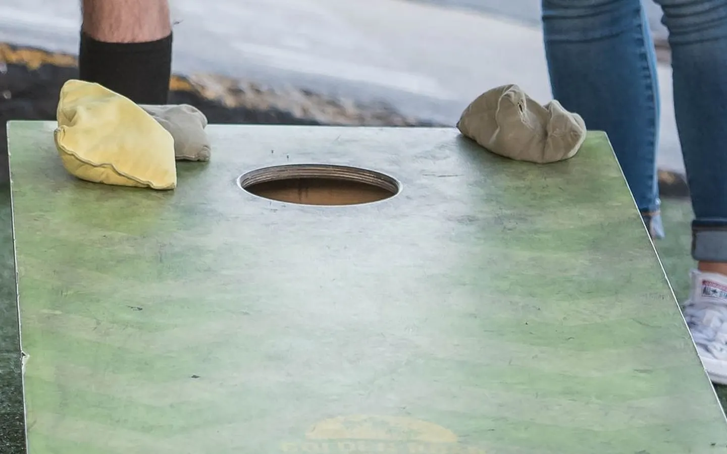Cornhole bags beside the hole on a green board
