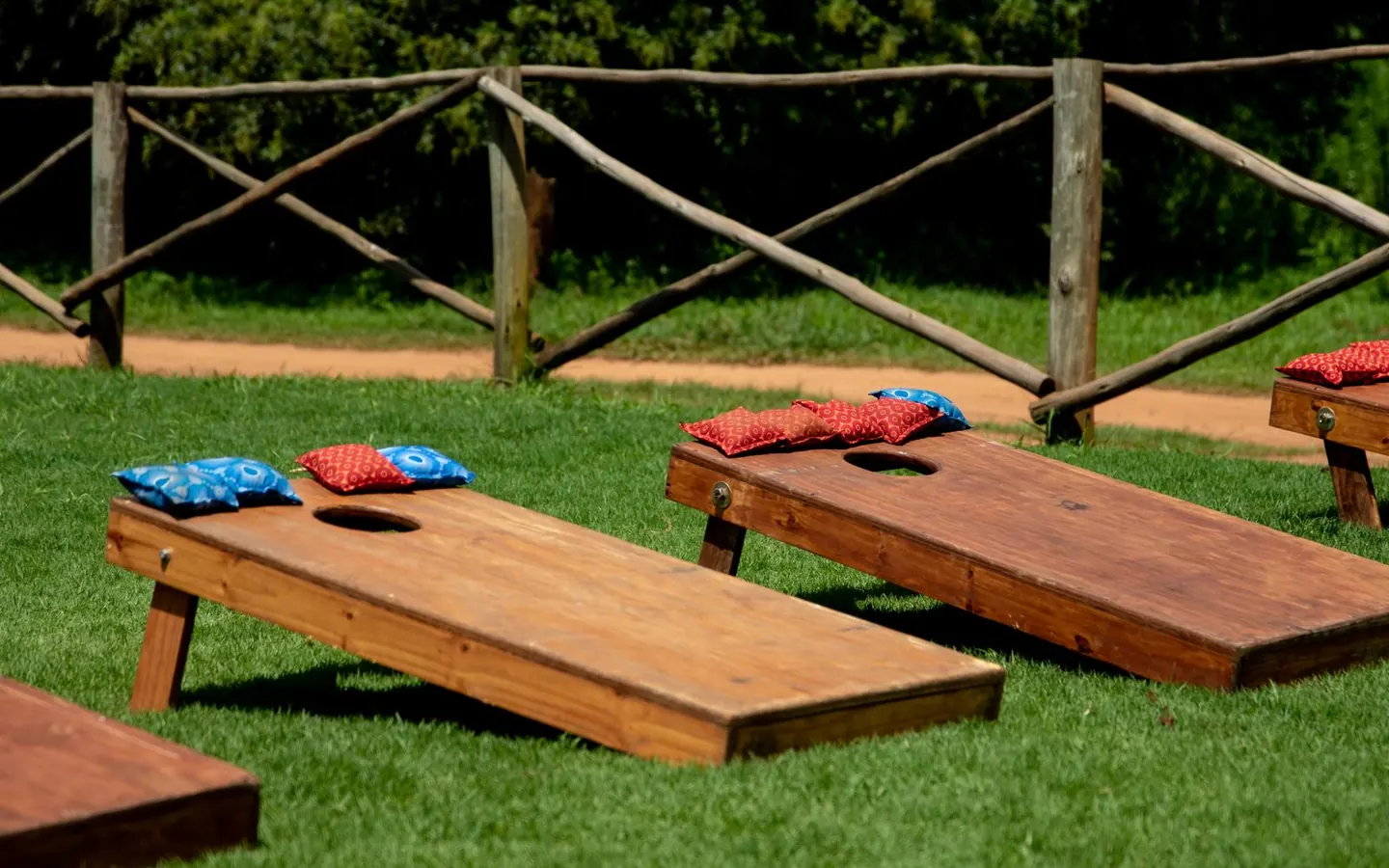 Wooden cornhole boards with red and blue bags on a green lawn