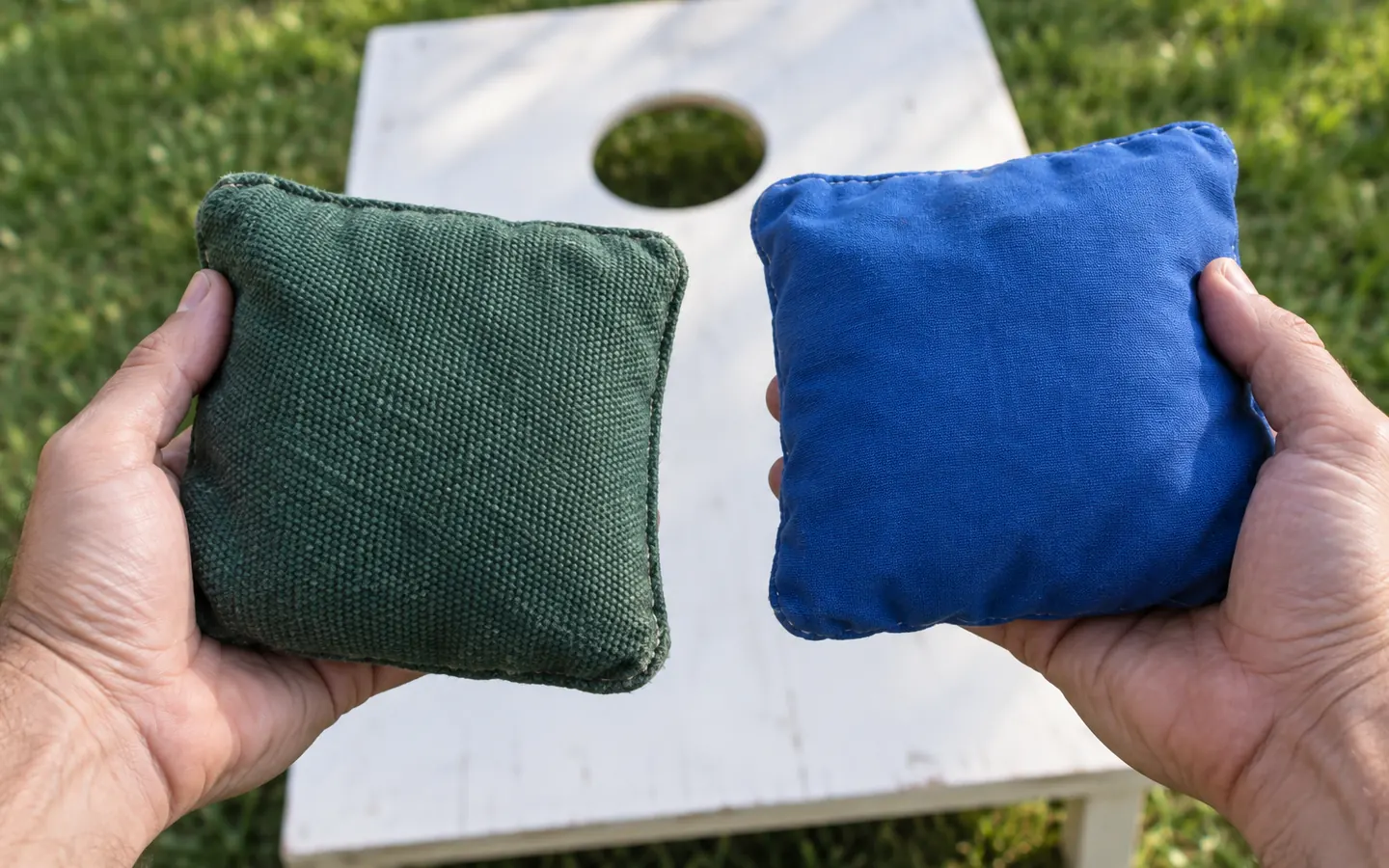 AI illustration of hands holding green and blue cornhole bags with different fabric textures