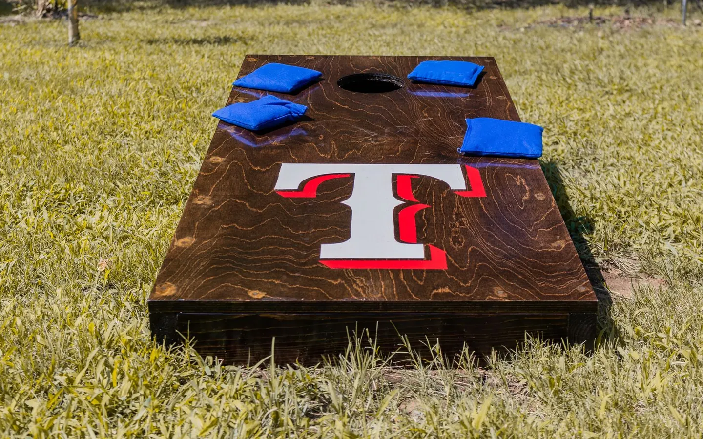 Wooden cornhole board and bean bags on a sunny lawn