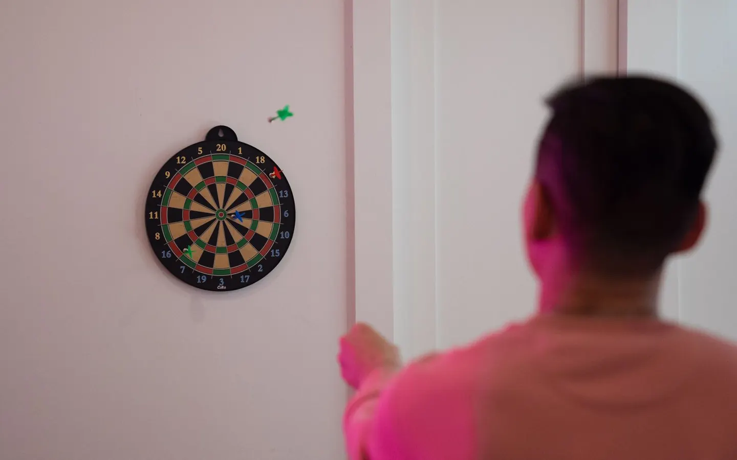 A player aiming a dart at an indoor dartboard
